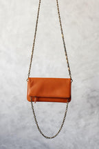 Bolso de piel naranja con dos cadenas