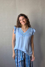 Blusa celeste raso con puntilla y volante en la manga