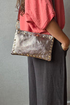 Bolso de piel tipo sobre con tachas cobre