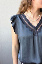 Blusa gris oscuro de raso con puntilla y volante en la manga