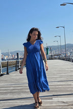 Vestido largo azulón con fruncido, escote en pico y volantes en manga y falda. Elegante y femenino. Envío desde España.